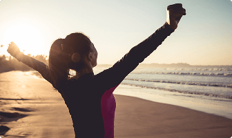 Woman on a beach holding her hands up